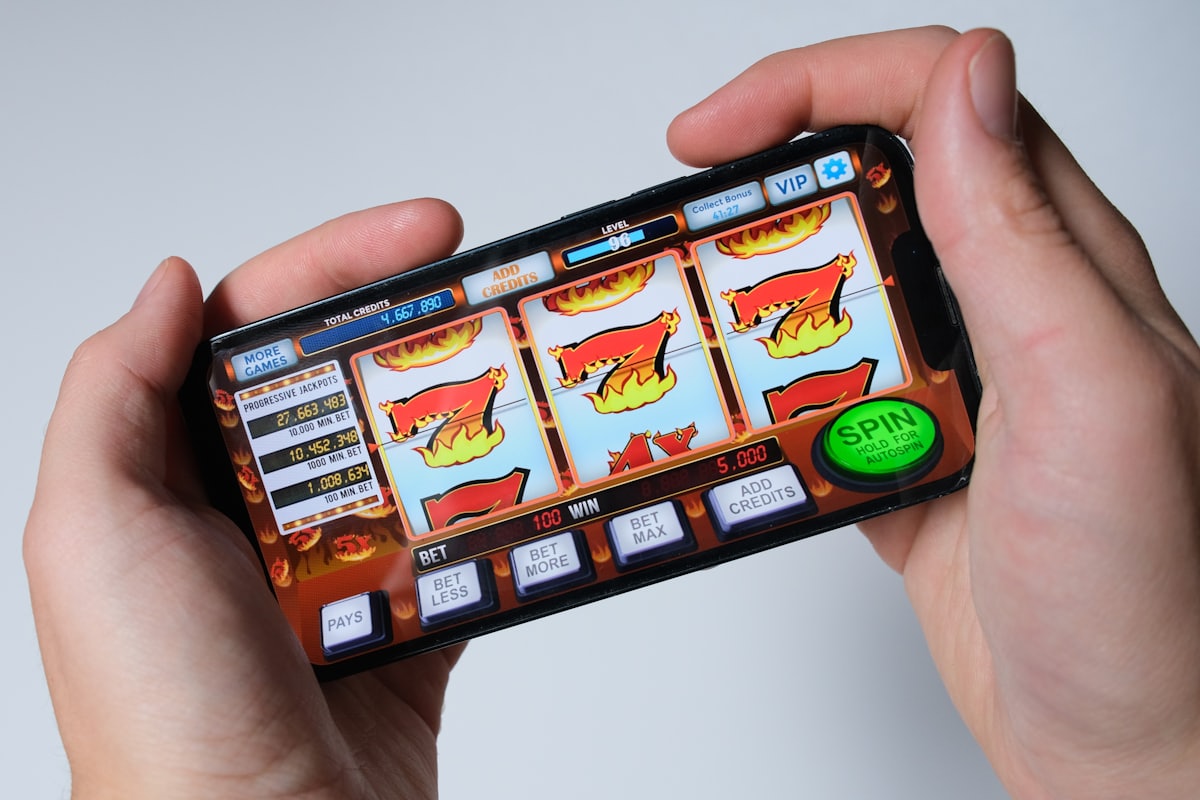 Seseorang memainkan permainan slot di layar ponsel, mewakili pemilihan judul slot berdasarkan RTP dan volatilitas