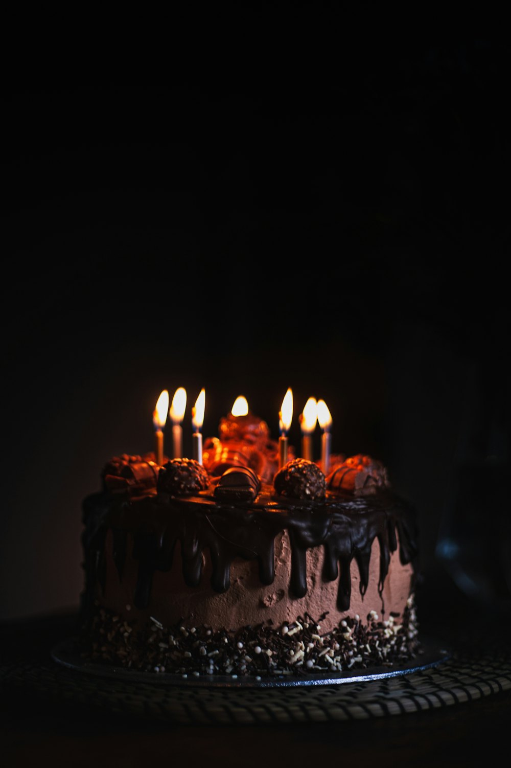 Kue cokelat dengan lilin menyala di latar gelap, melambangkan bonus ulang tahun